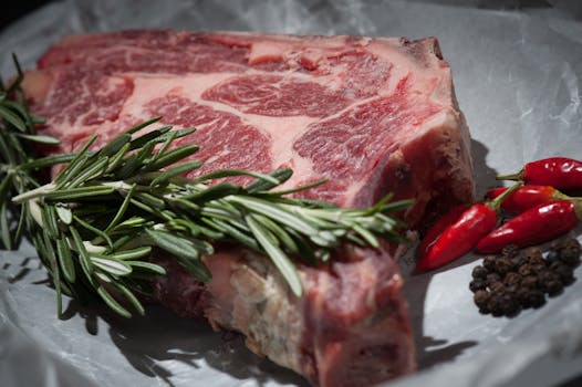 A raw steak garnished with rosemary and chilies.