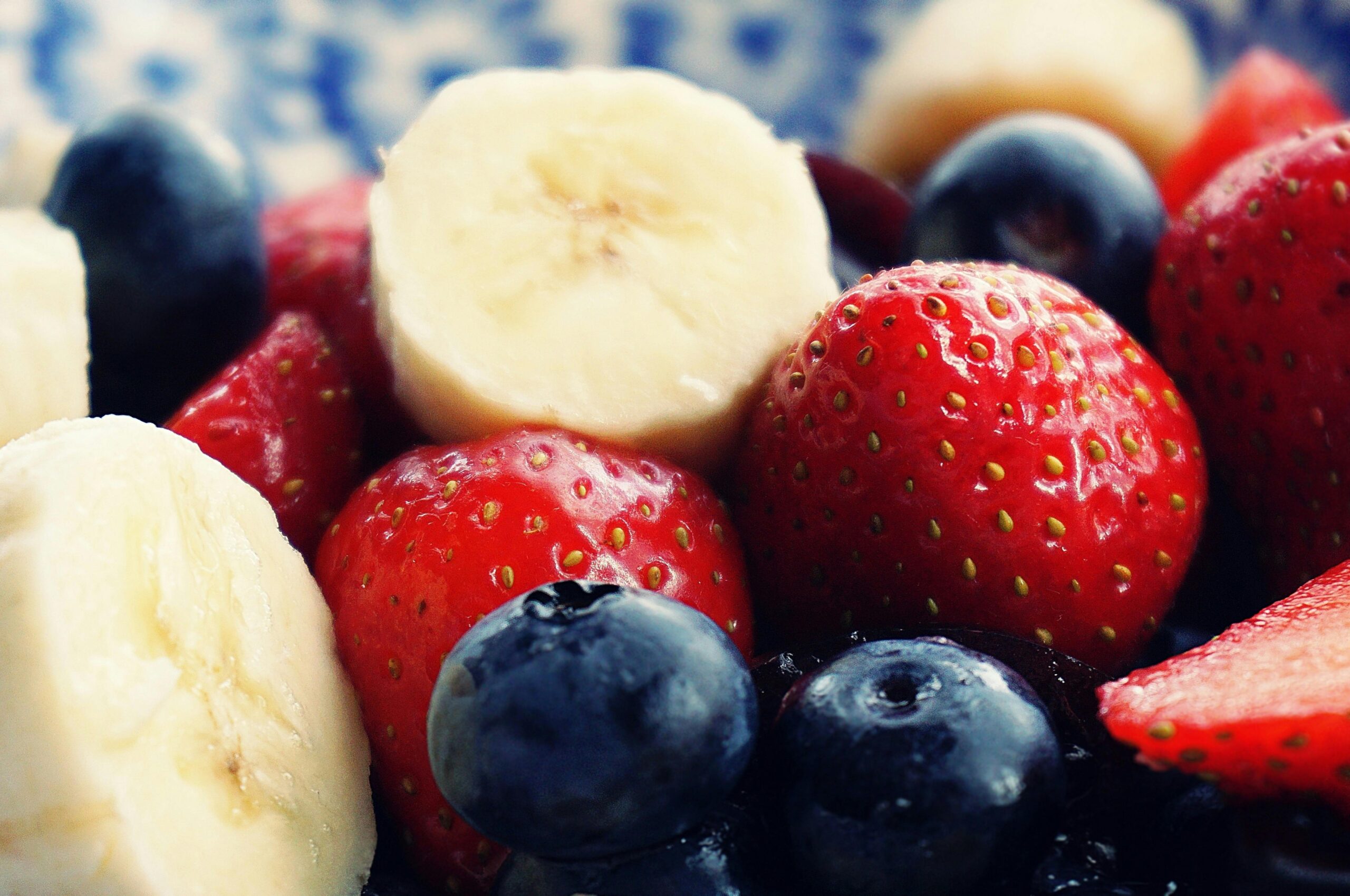 Close-up of fresh bananas, strawberries, and blueberries.