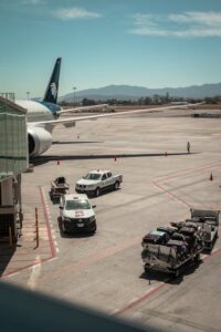 Airplane parked at Guadalajara airport with ground vehicles and luggage carts nearby.