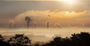 Smoke rising from factory chimneys at sunrise, resulting in air pollution.